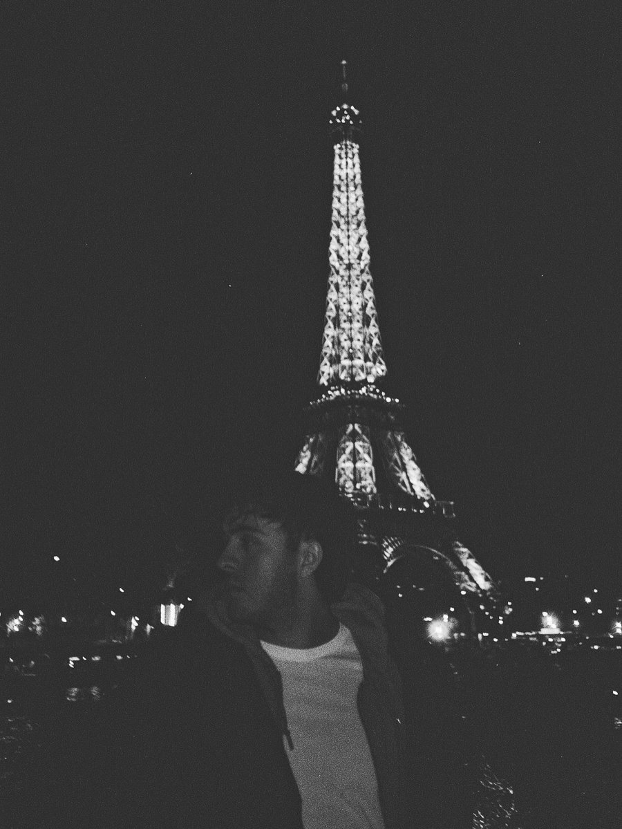 Portrait de Tom de Gorguette d'Argoeuves devant la tour Eiffel, de nuit